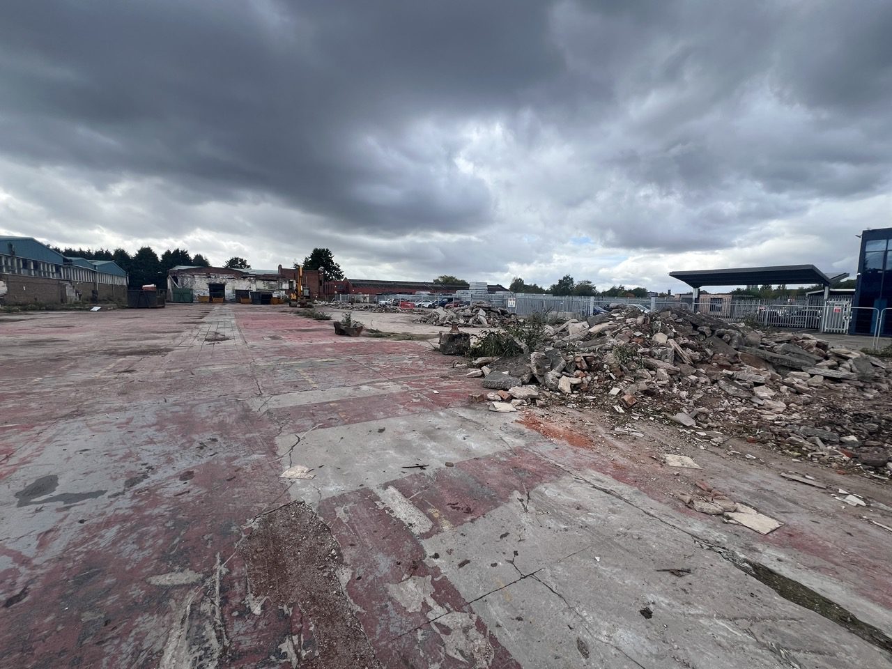 Existing concrete yard at the Wolverhampton site with demolition rubble stockpiled along the boundary