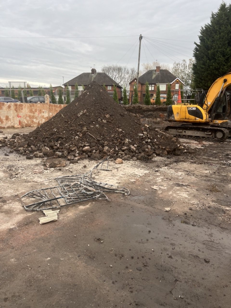 JCB excavator alongside a large stockpile of spoil and hardcore at a Wolverhampton site