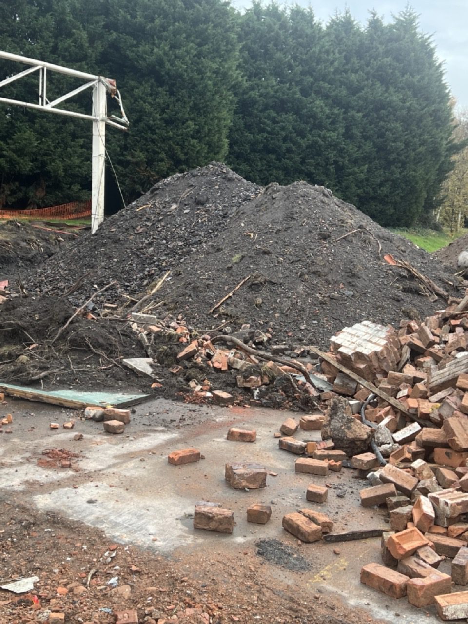 Spoil and rubble stockpile with newly planted conifer screening behind