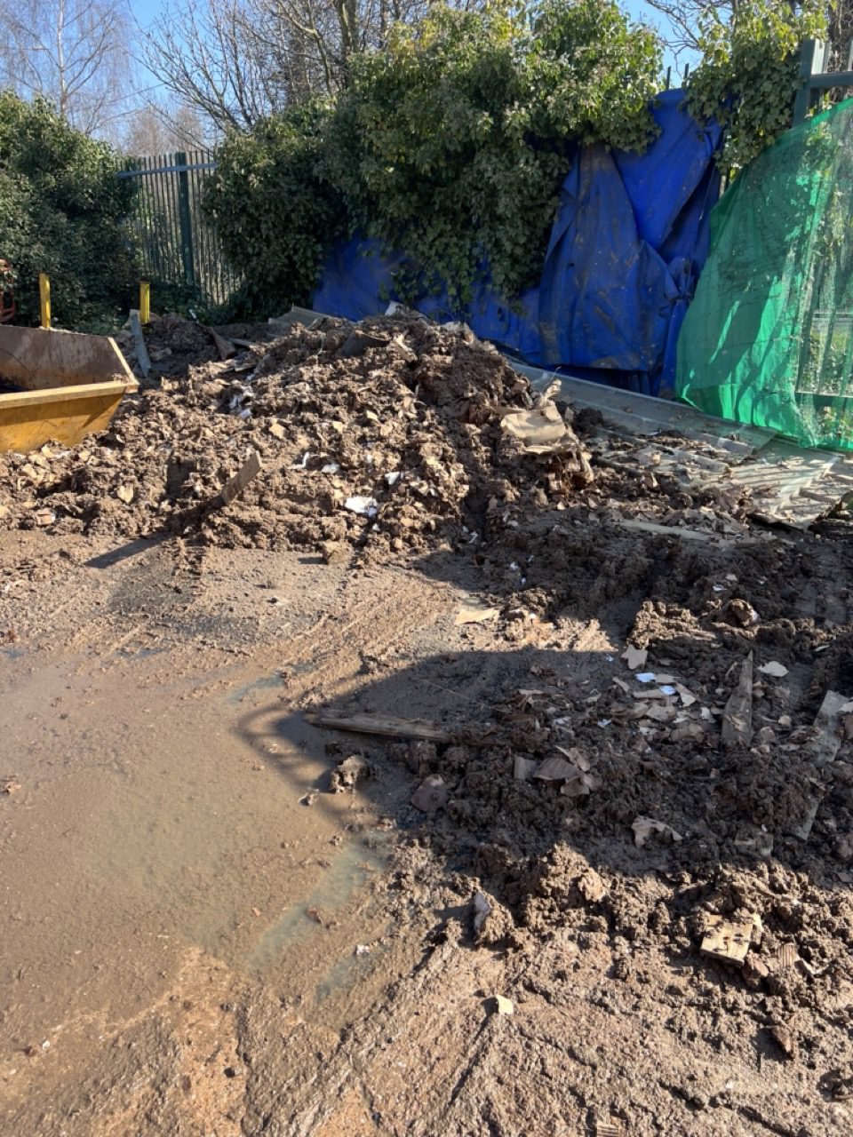Contaminated cardboard and soil waste scraped into piles ready for grab lorry removal