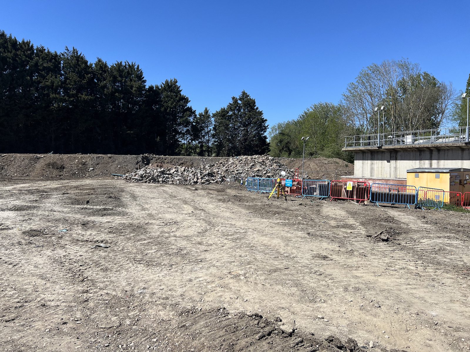 Partially cleared Coventry site with segregated stone stockpile and site barriers