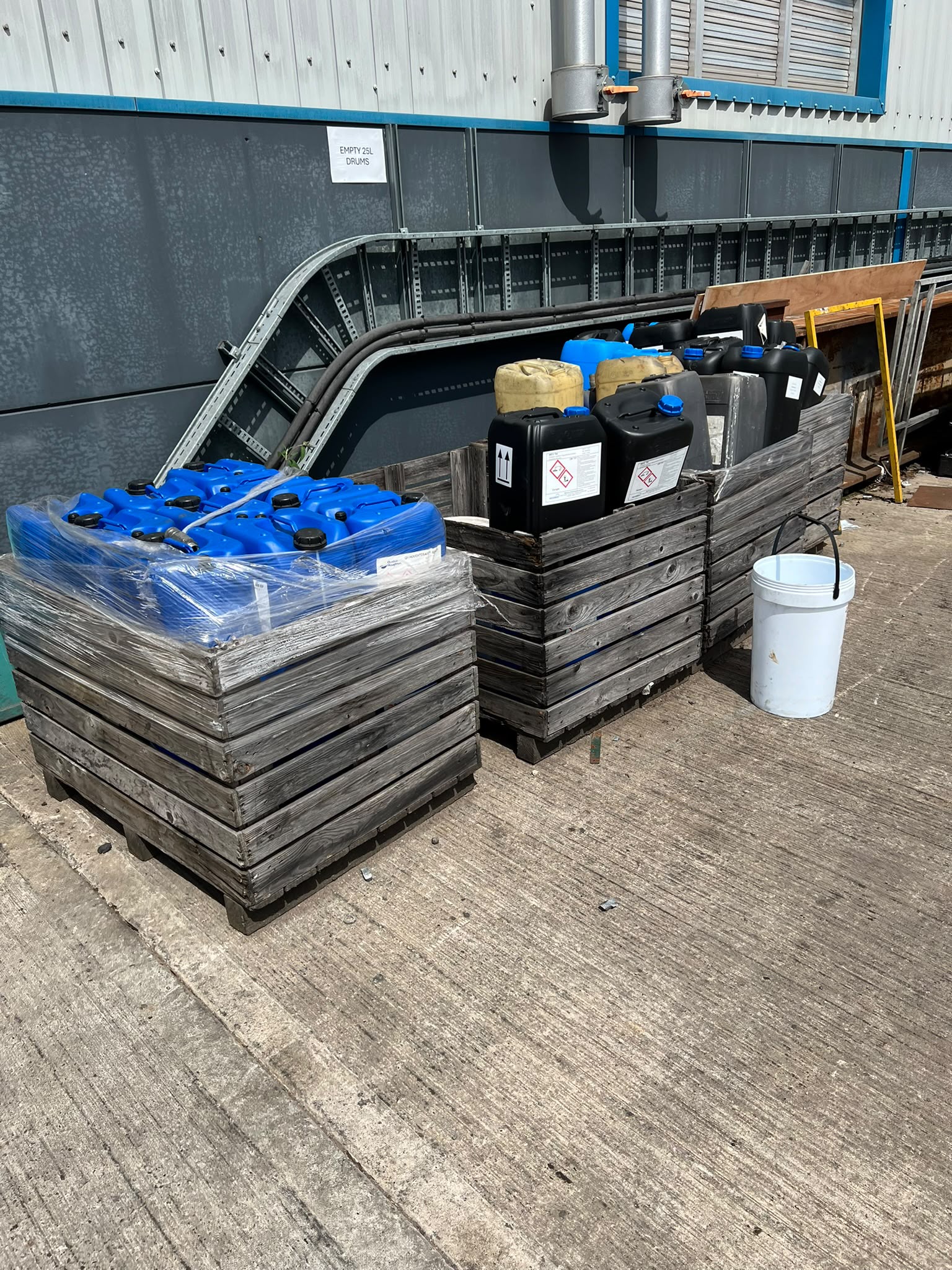 Pallets of 25-litre chemical tubs awaiting compliant hazardous collection
